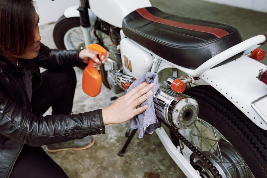 top angle view cropped biker polishing pipe his motorcycle(1)